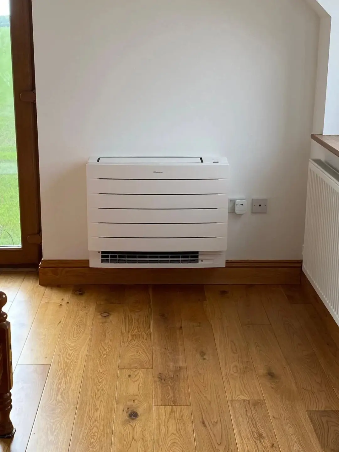 White floor console air conditioner on an oak floor