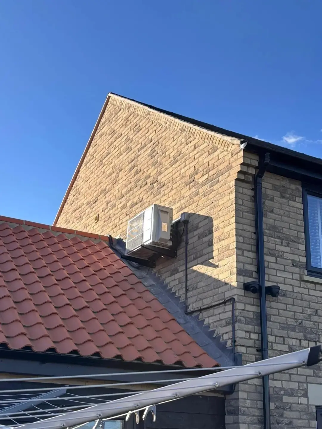 Air conditioning outdoor unit fitted high on a brick gable wall