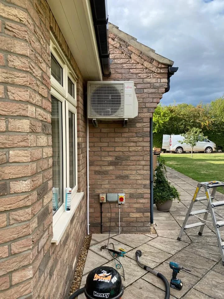 Air conditioning outdoor unit fitted on a brick house wall