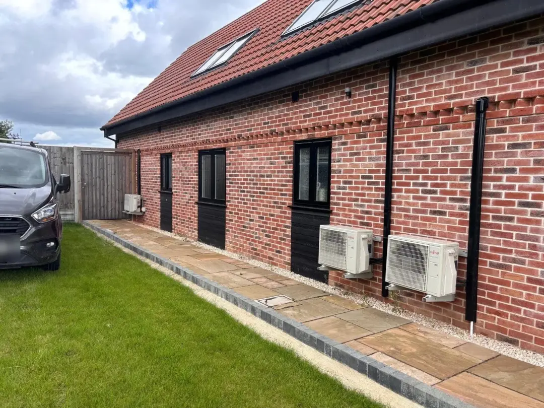 Two air conditioning outdoor units on a brick house wall